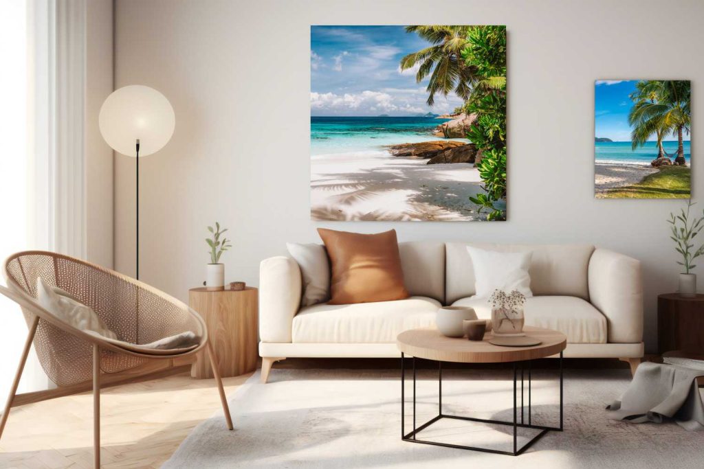 A modern living room with a white sofa, brown and beige pillows, a round coffee table, and tropical beach artwork on the wall. Order custom photo prints for a personal touch. A wicker chair and floor lamp complete this cozy, inviting space. Prints 4 You